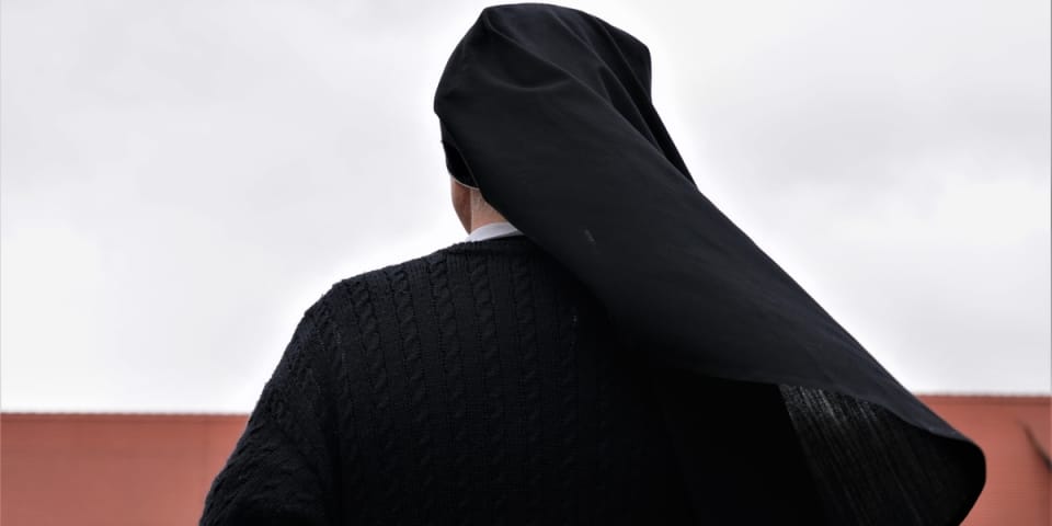 achristiannunseenfrombehindlookingattheoldmonasterygermanytraditionalblackclothesgrayautumndaybackgroundshutterstock1584907333