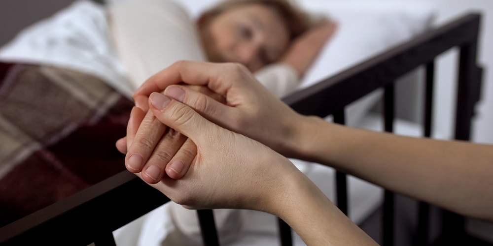 web2daughtersupportingherterminallyillmotherlyingonhospitalbedhospiceshutterstock1469279750